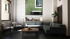 A modern living room with a sectional sofa, a small round coffee table, a floor lamp, and a large mirror. - EL Colonial Hotel Open Bar Adults Only (San Juan)
