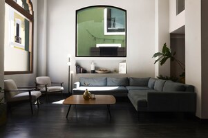 A modern living room with a sectional sofa, a small round coffee table, a floor lamp, and a large mirror.