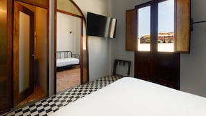 A room with a bed, a television mounted on the wall, and a checkered floor. - EL Colonial Hotel Open Bar Adults Only (San Juan)