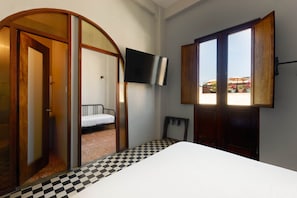 A room with a bed, a television mounted on the wall, and a checkered floor. - EL Colonial Hotel Open Bar Adults Only (San Juan)