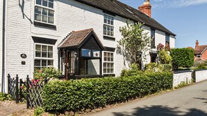 A white building with a black front door and a small porch. There is a sign above the door and a number '10' on the wall. - A wonderful three bedroom cottage sleeping six. (Hartlebury, near Kidderminster)