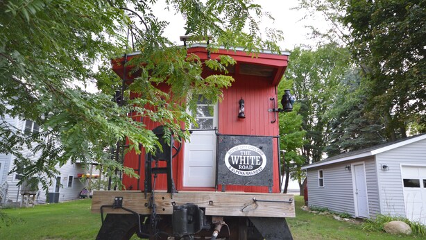 En rødviolet og hvid bagvogn med et skilt, der viser: "Boyne City Gaylord The White Road & Alpena Railroad".