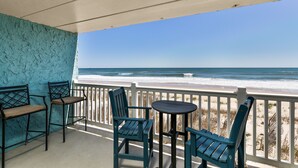 A balcony with a view of the ocean, featuring two chairs and a small table.