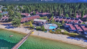 Vista aérea de una zona residencial costera con casas, una playa y una piscina azul cristalina.