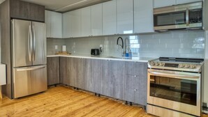 Una cocina moderna con un refrigerador de acero inoxidable, un horno empotrado y un microondas.