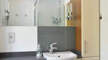 A modern bathroom with a white sink, a mirror, and a shower.