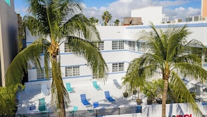 A hotel with a white facade, blue accents, and a pool area with lounge chairs. - Best Beach Location | Wi-Fi, TV & Amenities (Miami Beach)