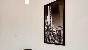 A modern dining area with a glass table, two black chairs, a pendant light, and a framed black and white photograph on the wall. - Best Beach Location | Wi-Fi, TV & Amenities (Miami Beach)
