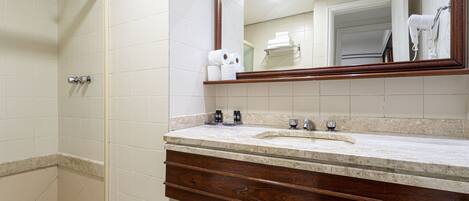 Une salle de bain avec une douche, un lavabo avec un miroir et des articles de toilette sur le comptoir.