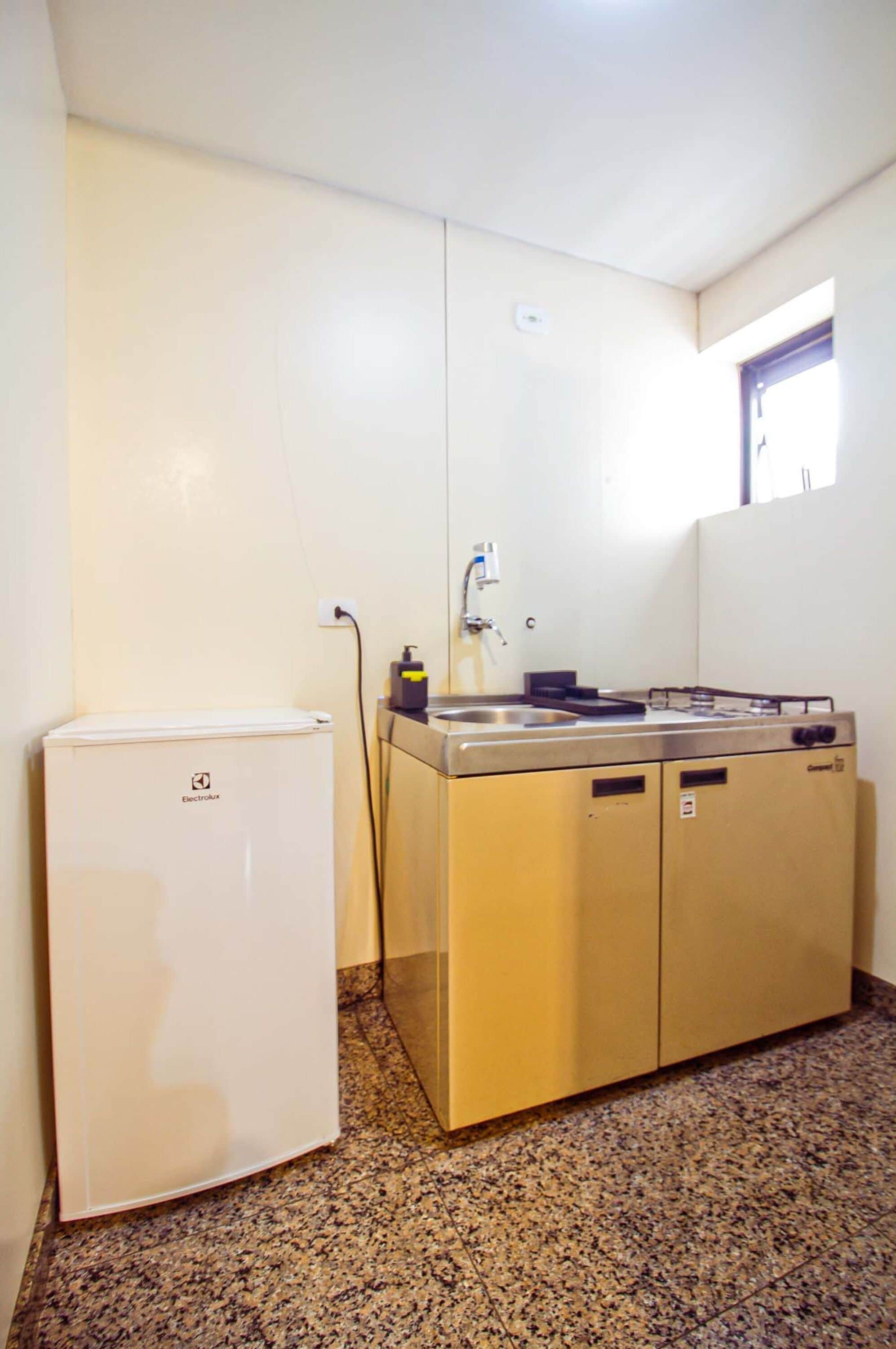 Una kitchenette compacta con estufa integrada, lavamanos y un refrigerador pequeño.