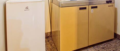 Una kitchenette compacta con estufa integrada, lavamanos y un refrigerador pequeño.