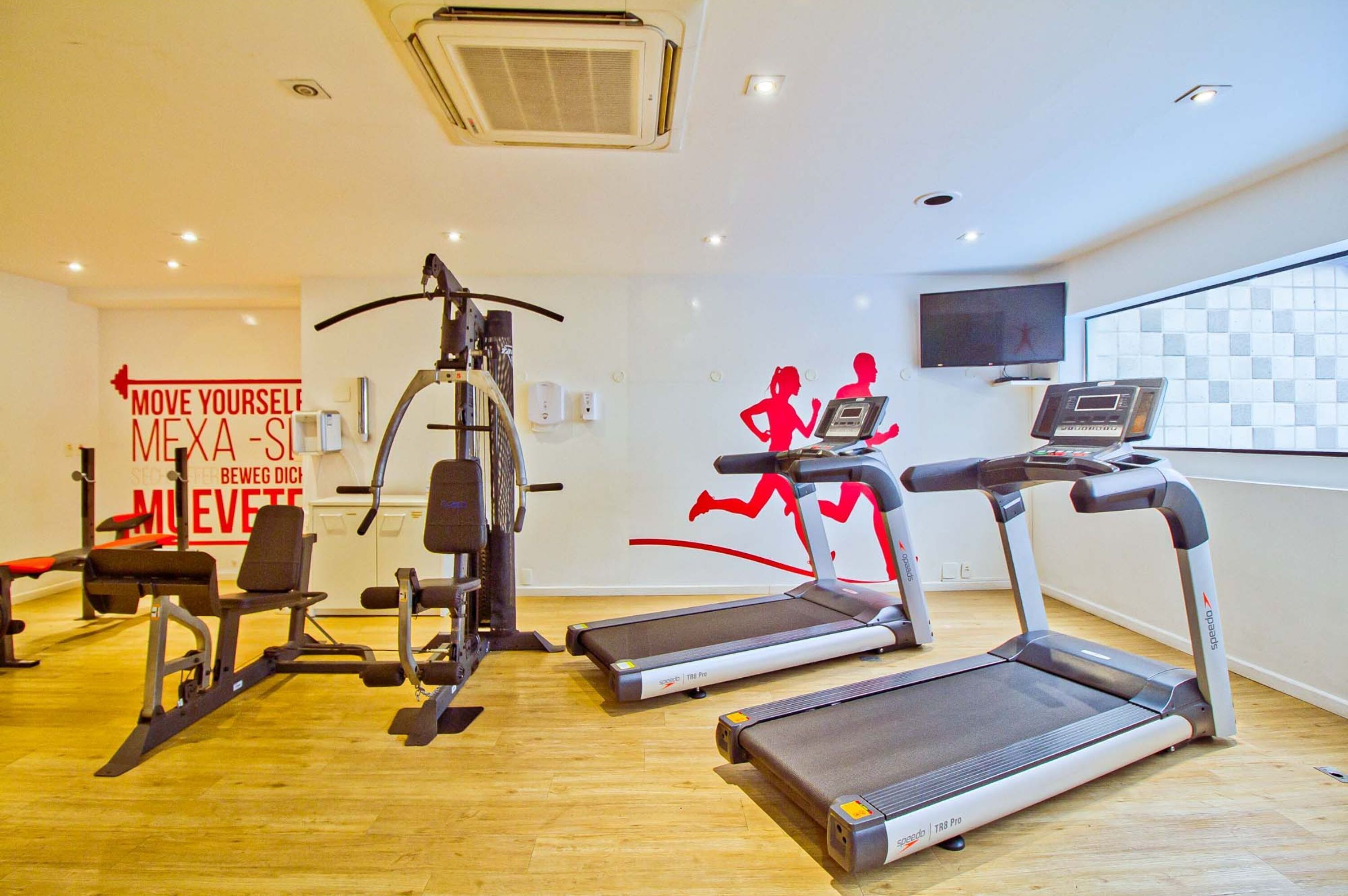 A gym with treadmills, weight machines, and a motivational sign.