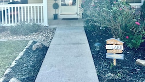 A house with a front porch, a welcome sign, and a driveway leading to the entrance.