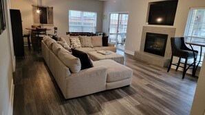 A modern living room with a sectional sofa, a fireplace, and a dining area with a table and chairs.