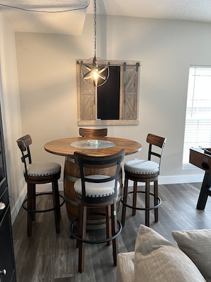 A dining area with a round wooden table, four chairs, a hanging light fixture, and a rustic wooden wall panel. - Beautiful lakefront house - calm cove, boat slip, amazing views, best location!  (Osage Beach)