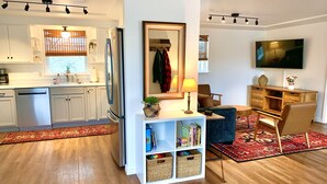 Eine moderne Küche mit weißen Schränken, einem Edelstahl-Kühlschrank und einem Essbereich mit einem blauen Sofa und einer Holzsideboard.