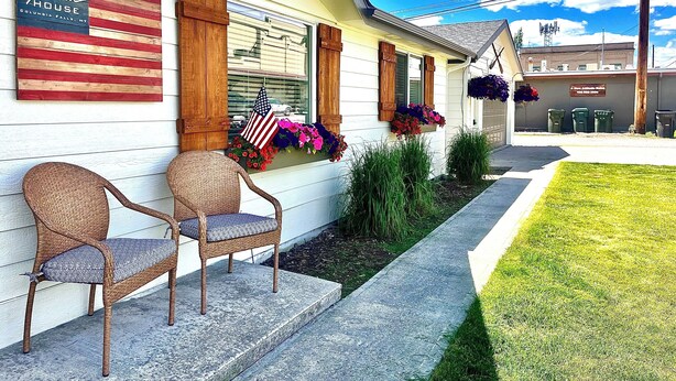 Ein Motel mit Veranda, Korbstühlen, einer US-amerikanischen Flagge und Blumenkästen.
