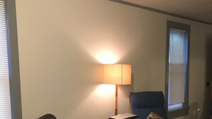 Un salon avec un canapé en cuir, un fauteuil bleu, une table basse en bois et un lampadaire.