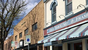 Une vue de rue avec un bâtiment portant l’inscription « Old Town Art & Frame » et un panneau indiquant des places de stationnement réservées aux personnes handicapées.