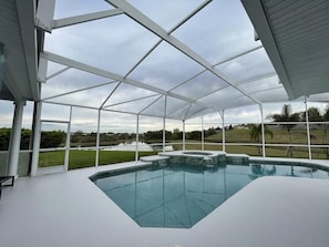 A covered swimming pool with a view of a lake and surrounding landscape.