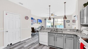 A modern kitchen with grey cabinets, a white dishwasher, and a granite countertop. - Disney | Townhouse | Pool | Windsor Hills (Kissimmee)