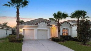 A residential house with a two-car garage, a well-maintained lawn, and palm trees. - 4BR Disney | Pool&Spa | Windsor Hills | Arcade Style Gameroom (Kissimmee)