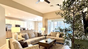 A modern living room with a sofa set, a coffee table, and a large plant. - 4BR Disney | Pool&Spa | Windsor Hills | Arcade Style Gameroom (Kissimmee)