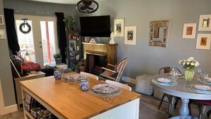 A dining area with a wooden island, a fireplace, and a television on the wall.