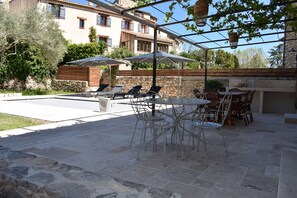 Um pátio externo com piscina, espreguiçadeiras e guarda-sóis.