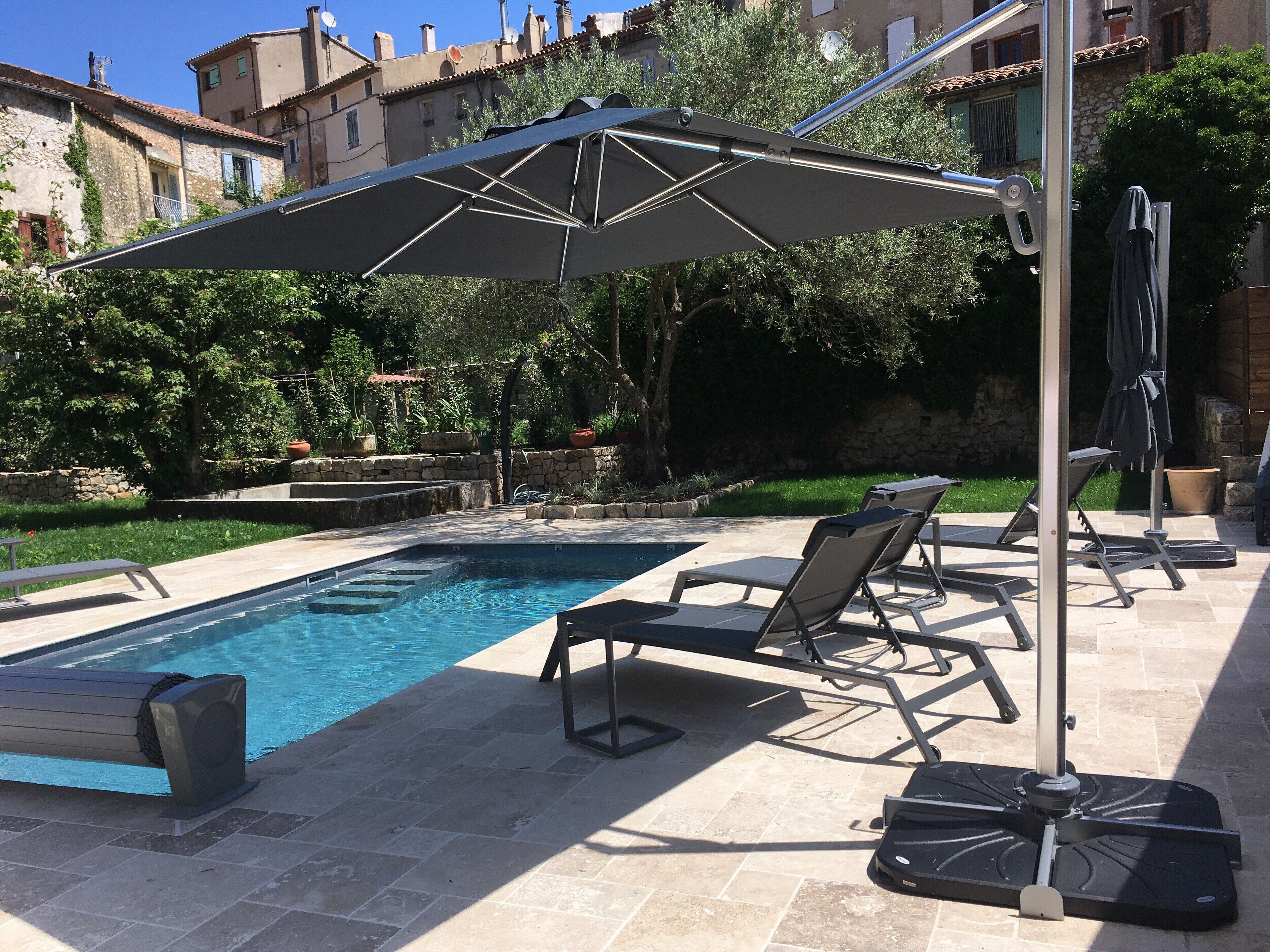 A swimming pool with lounge chairs and an umbrella.