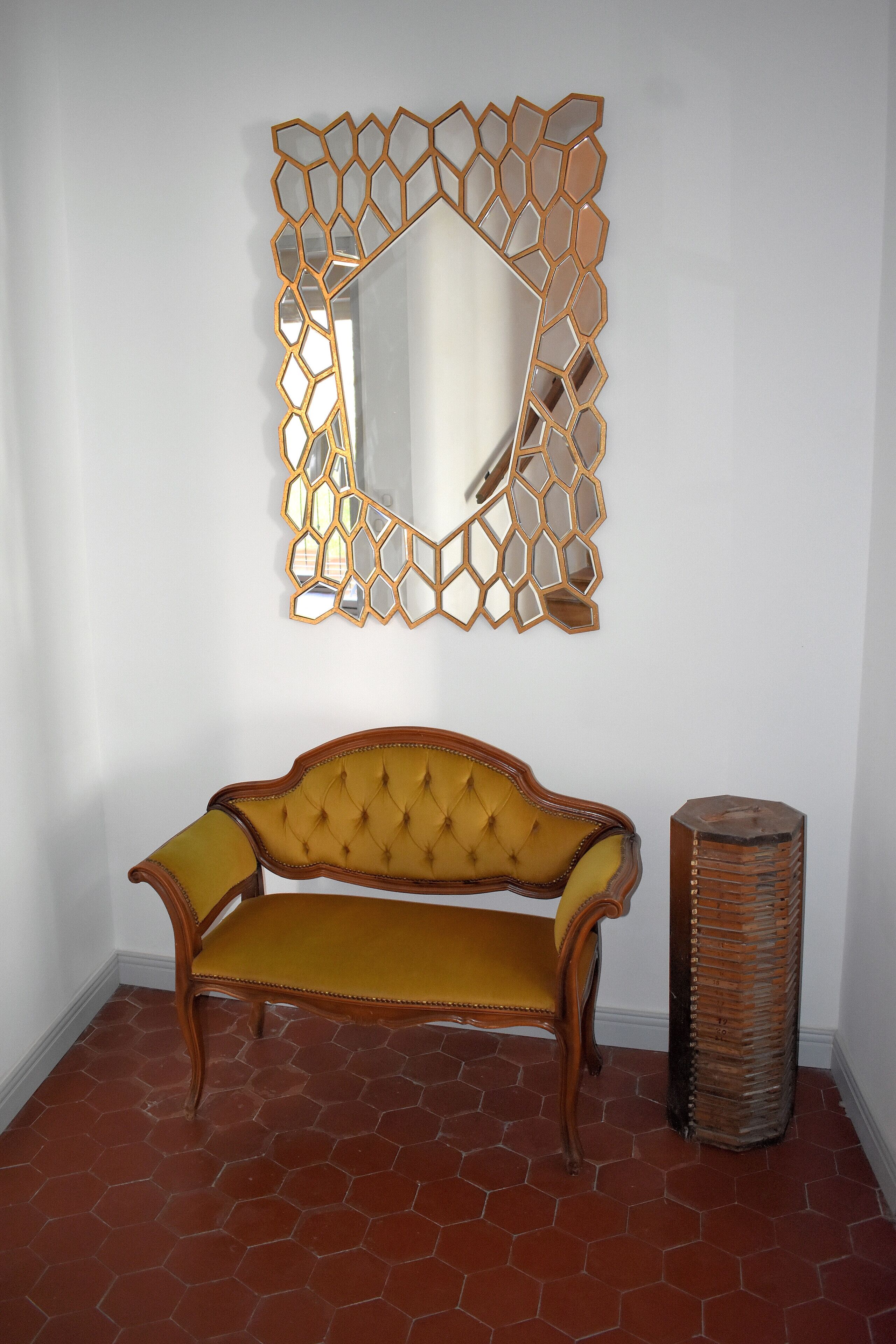 Ein Zimmer mit einer Holzbank, einem hohen gewebten Korb und einem Wanddekor.