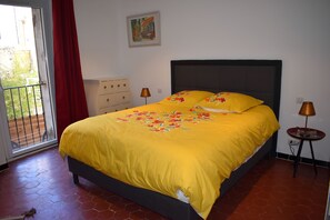 Quarto com cama, penteadeira, luminária e um quadro na parede.