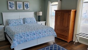 A bedroom with a bed, nightstands, a dresser, and a window with blinds.