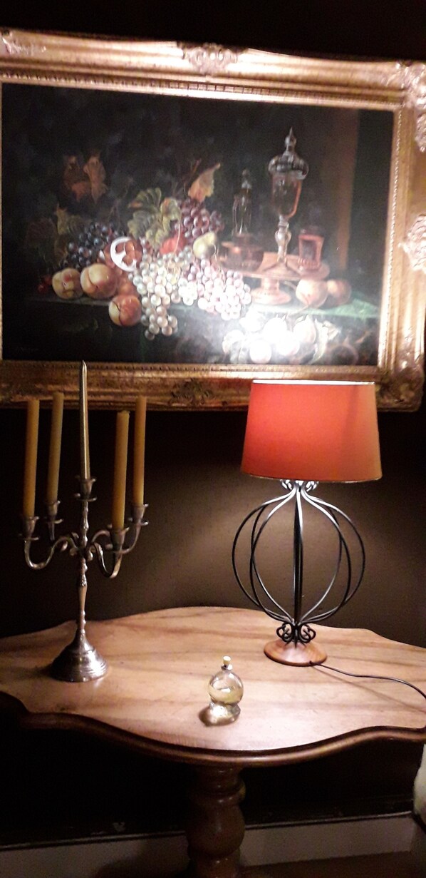 A table with a candelabra, a lamp, and a decorative item. - Charming village house with swimming pool in the heart of Sologne (Nançay)