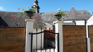 A gated entrance with a tiled roof, a wooden fence, and flower pots on top.