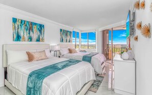 A modern bedroom with two beds, large windows, and artwork on the walls. - One-of-a-Kind Oceanfront, Designer Furnished, Luxury Condo w/ Resort Amenities (Myrtle Beach)