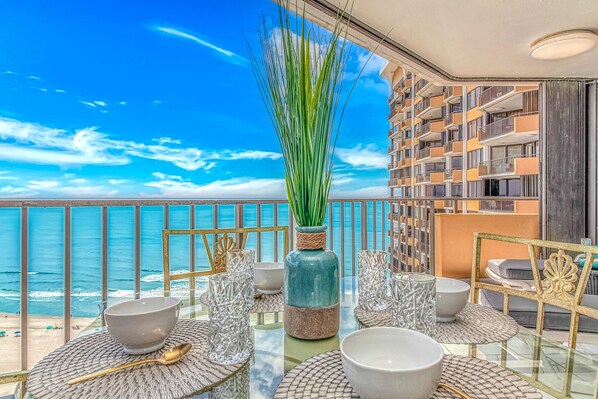 A balcony with a view of the ocean, furnished with tables, chairs, and decorative items. - One-of-a-Kind Oceanfront, Designer Furnished, Luxury Condo w/ Resort Amenities (Myrtle Beach)
