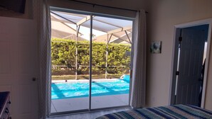 Un dormitorio con un amplio ventanal corredera que da a una zona de piscina.