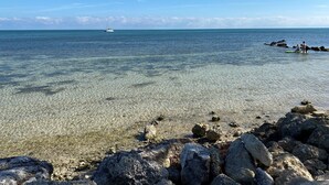 Une plage dégagée, avec des rochers visibles et un bateau au loin.