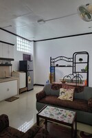 Un espacio habitable compacto con kitchenette, un sofá, una mesa de comedor y un ventilador de techo.