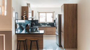 Een moderne keuken met een centraal eiland, houten kastjes en roestvrijstalen apparatuur.