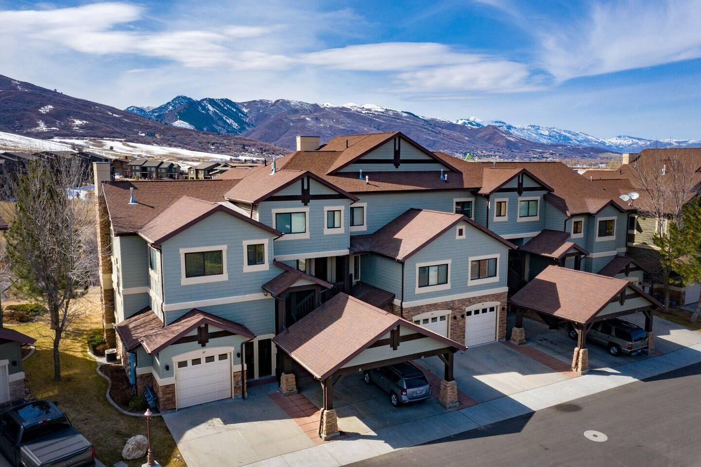A cluster of two-story houses with attached garages, set against a mountainous backdrop.