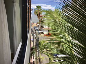 A view from a balcony overlooking a street with parked cars and a palm tree. - Pilitas Vallarta Apartments (Puerto Vallarta)