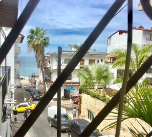 A coastal street with buildings, parked cars, and palm trees. - Pilitas Vallarta Apartments (Puerto Vallarta)