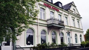 En historisk bygning med balkon og buede vinduer, med teksten 
