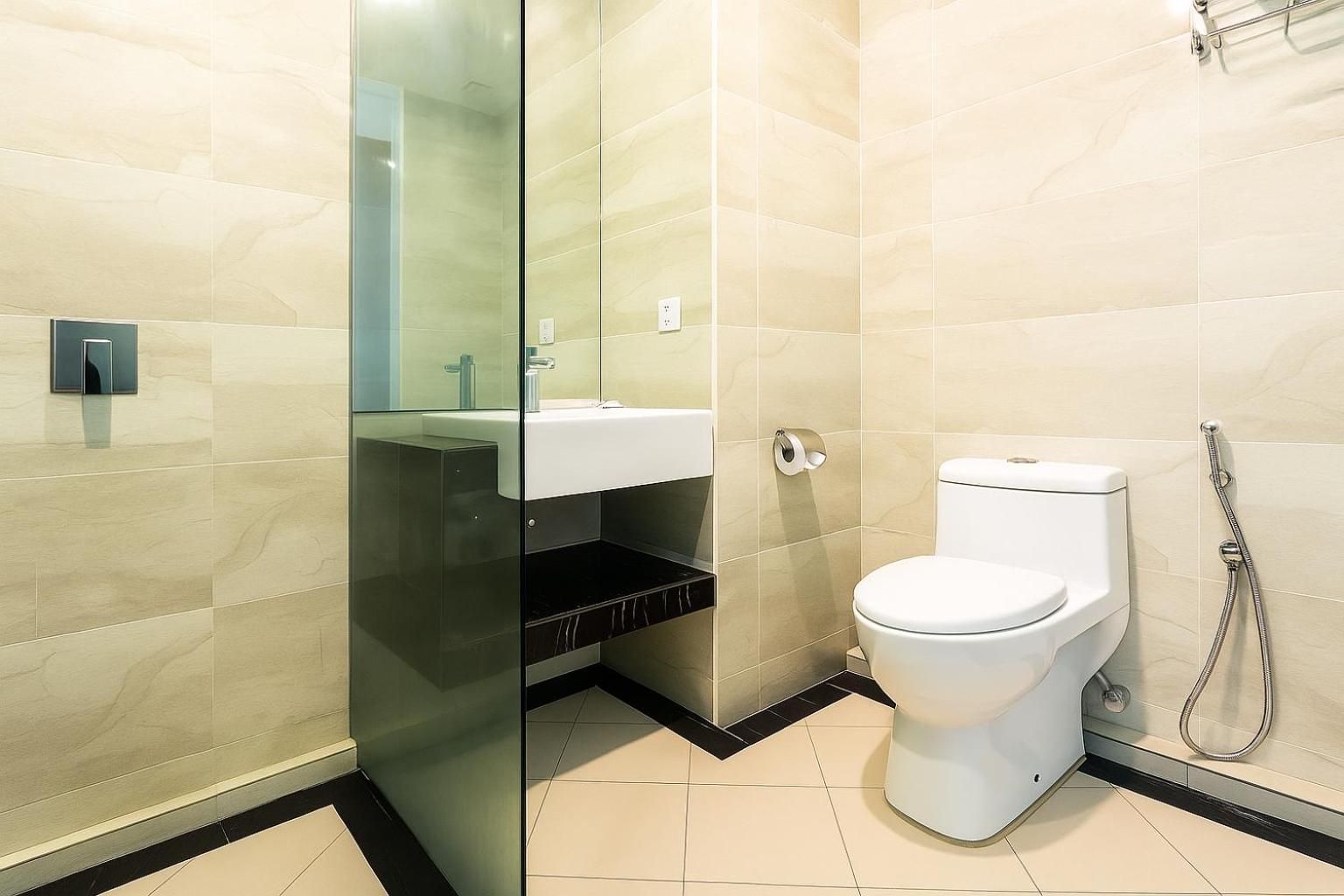 A modern bathroom with a toilet, a glass shower enclosure, and a sink.
