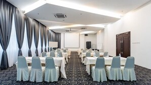 A conference room with tables and chairs, a projector screen, and a door. - THE Reed Hotel Melaka Formerly E-red Hotel Melaka (Malacca City)