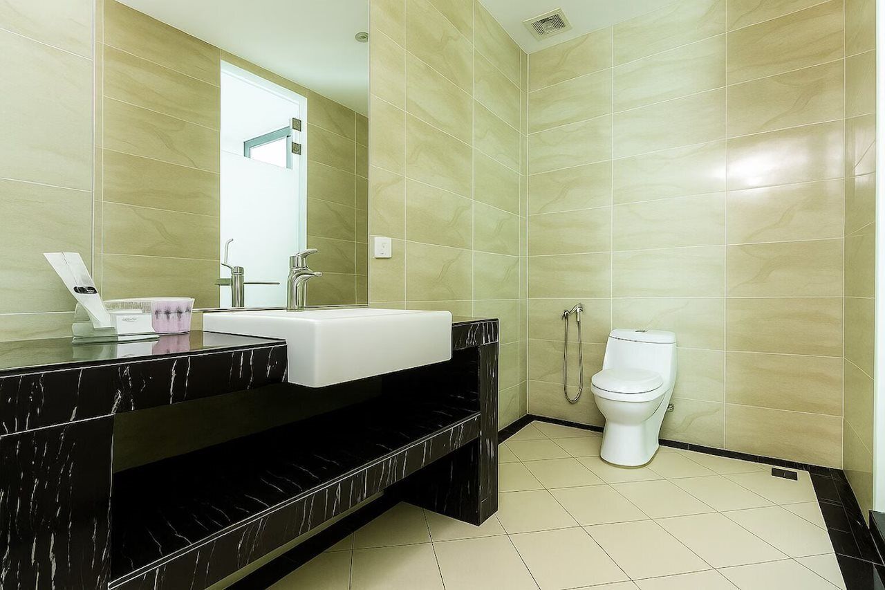 A modern bathroom with a black marble countertop, a white sink, and a toilet.