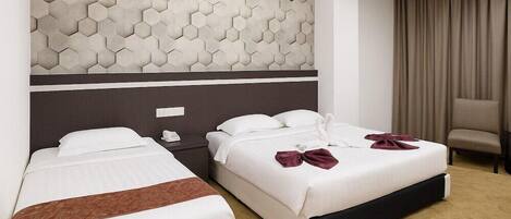 Two beds with white linens, a brown throw, a headboard with a hexagonal pattern, a chair, and a curtain.