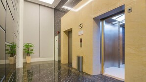 A modern lobby with a marble floor, a reception desk, potted plants, and an elevator. - THE Reed Hotel Melaka Formerly E-red Hotel Melaka (Malacca City)